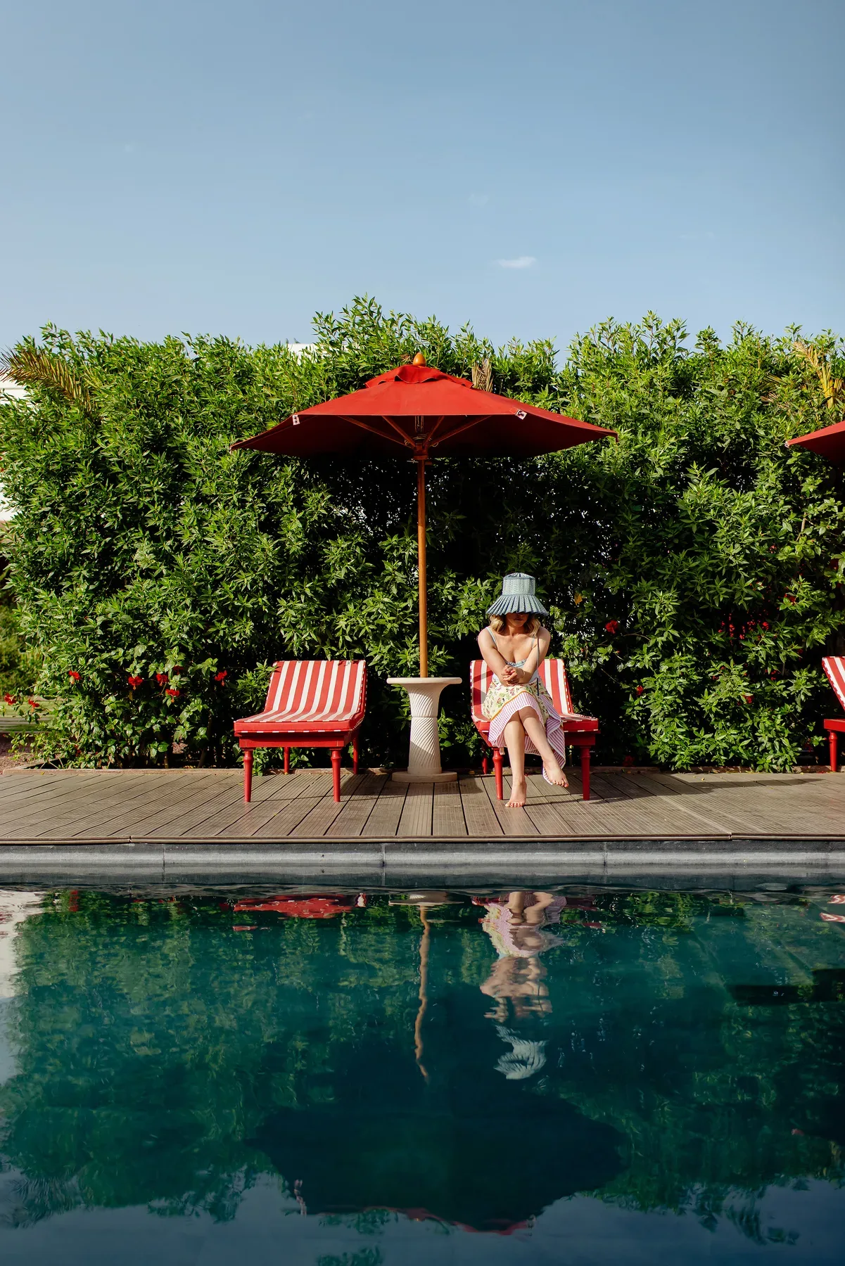 Woman relaxing on a red lounge chair beside a sparkling clean pool